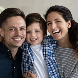 Man and woman smiling alongside their child