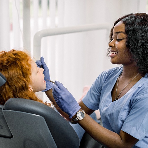 dentist working on young girl’s mouth 