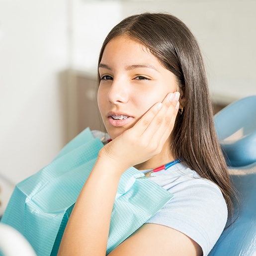 Teen girl holding cheek in pain