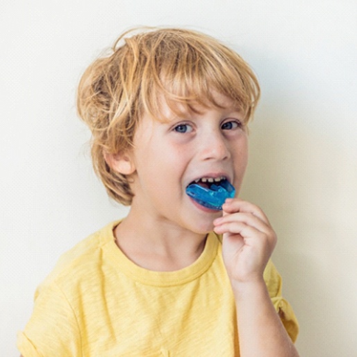 A little boy putting in a mouthguard