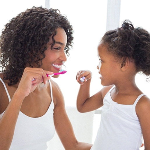 A mom and daughter brushing their teeth at home
