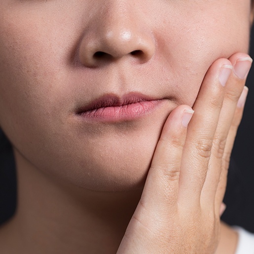 Child holding cheek in pain