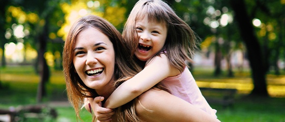 Mother giving daughter a piggy back ride