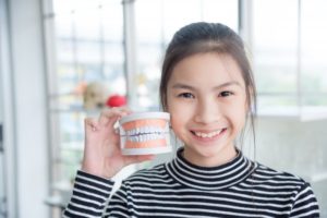 young child holding a model of a mouth and smiling