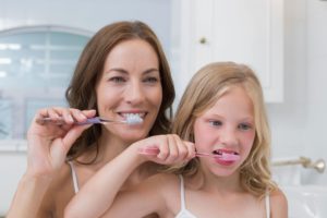 mom and daughter brushing teeth together