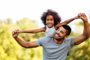 a parent carrying their child on their shoulders in a park