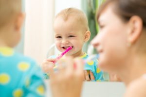 Parent brushing baby's teeth according to Willow Park pediatric dentist