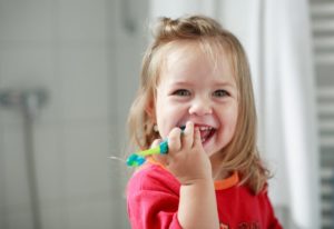 little girl holding a toothbrush from a children’s dentist in Willow Park 