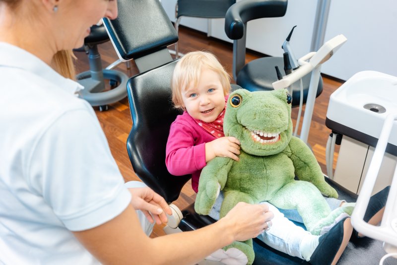 Child holding a stuffed dinosaur that has human teeth