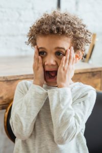 Scared young boy with hands on his face