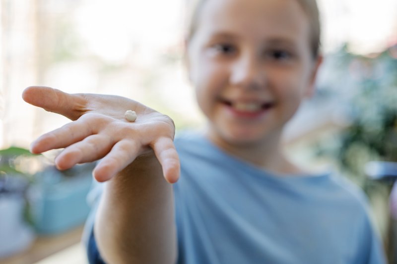 a child holding an extracted tooth